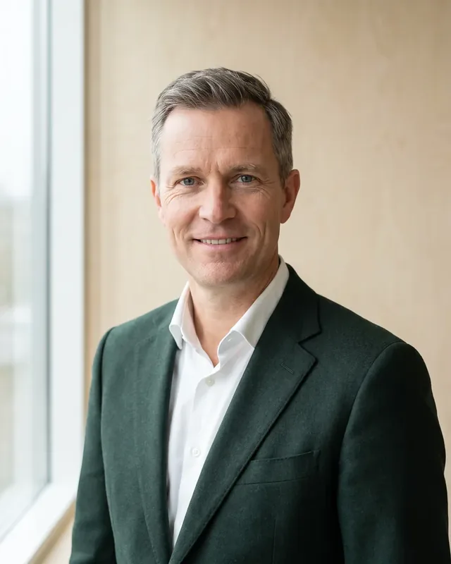 Tõnis Raidma smiling in a dark green jacket by an office window. New decking products spend a season outdoors at our Peetri warehouse before joining the range.