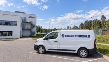 Päikesepaistel külgvaates valge väikekaubik TERRASSIEHITUSTALLINN.EE kirjaga Keila muusikakooli valge maja ja männide vahel, Keila jõe äärde on ehitatud 14 tõstetud laudisega terrassi.