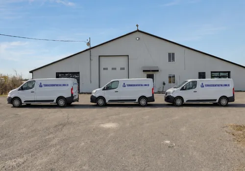Viilkatusega hall laohoone rulluksega, ees kruusaplatsil rivis kolm valget kaubikut, Peetri laost läks 2025. hooajal objektidele 2 236 terrassilauda.